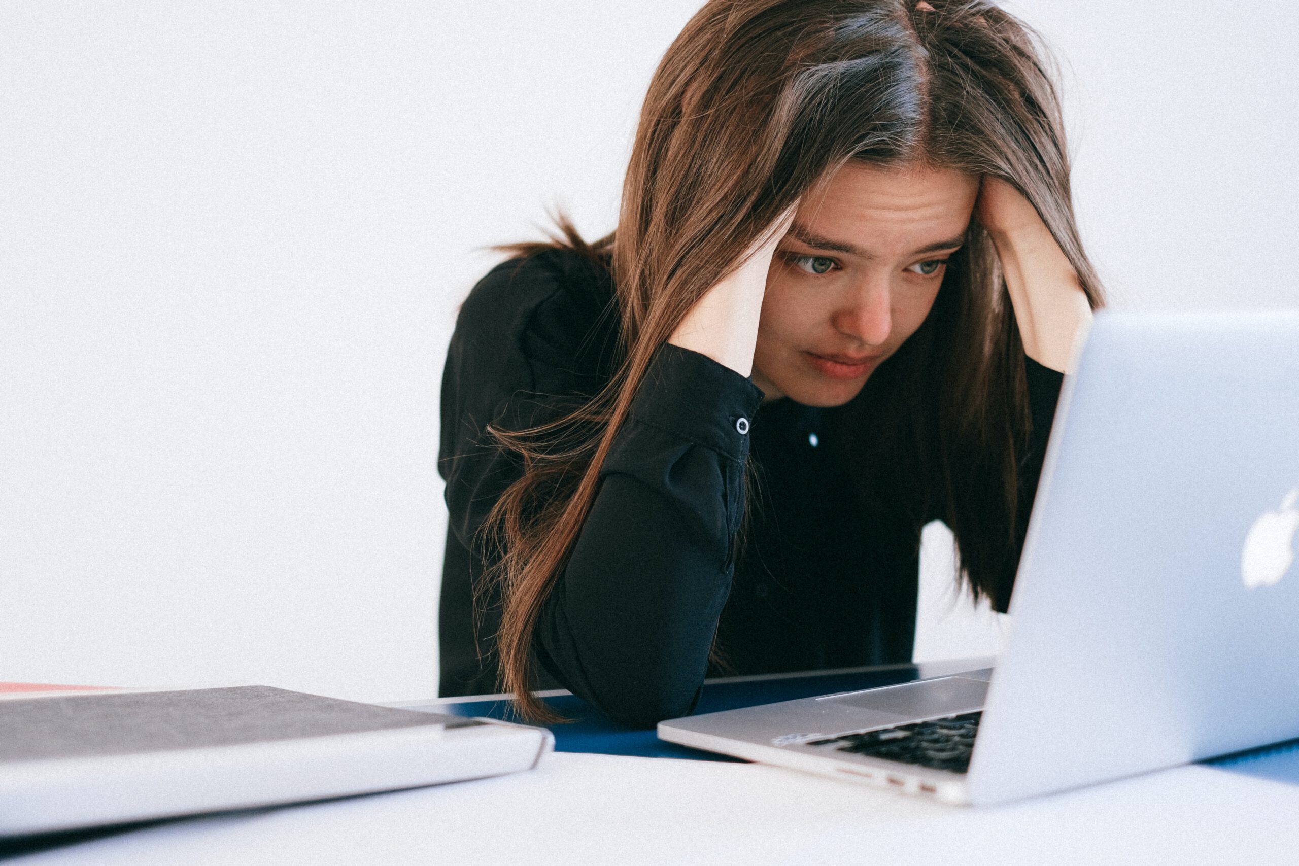 Załamana młoda kobieta na bezrobociu siedząca przed komputerem i szukająca pracy